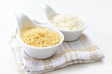 Short pasta spaghetti angel hair and uncooked rice displayed in containers on white background