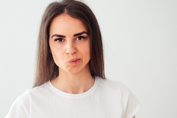 Skeptic and nervous young brunette on a light background, frowns upset because of a problem. Negative person.