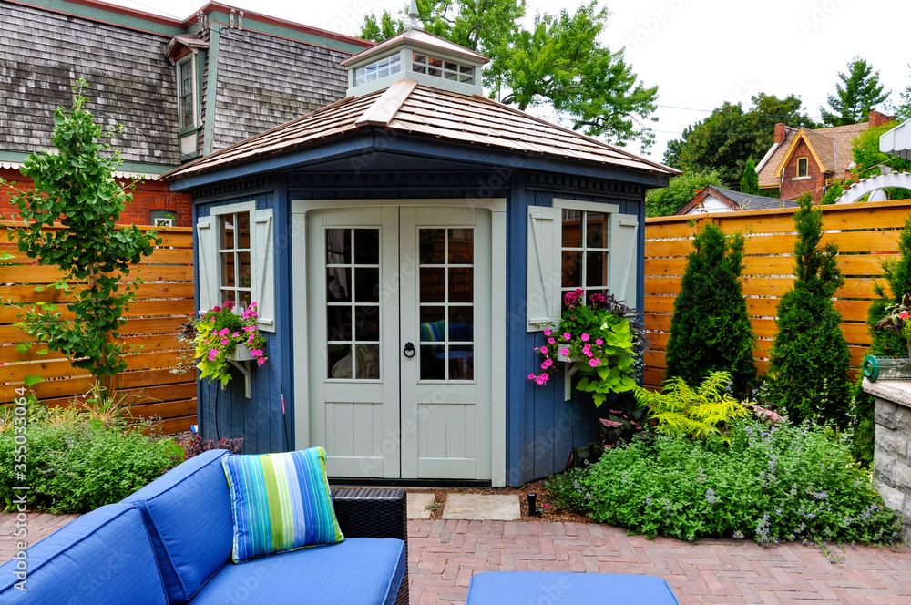 Wired with electricity and wifi, this large luxury backyard shed makes a perfect garden in the office while working from home.   - obrazy, fototapety, plakaty 