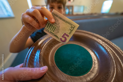 Boy putting offering in offering plate in church.