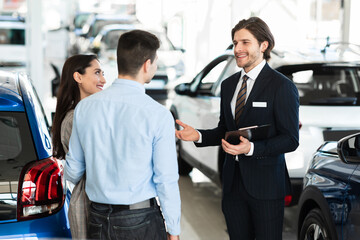 Salesman Offering Couple Car Standing In Office