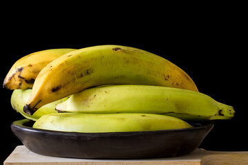 Plantain or Green Banana (Musa x paradisiaca) in a ceramic traditional dish on dark background