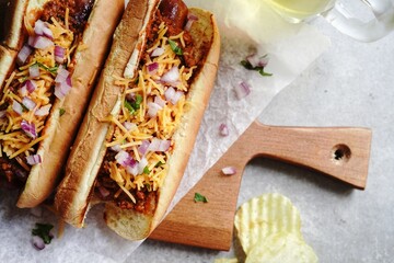 Homemade Chili dogs topped with cheddar cheese, selective focus