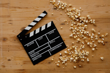 Filmmaking concept. Movie Clapperboard. Cinema begins with movie clappers. Movie clapper on an old wooden background and a scattering of popcorn.