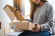 © Farknot Architect - A beautiful young asian woman receiving and opening a postal parcel box at home for delivery and online shopping concept