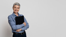 Portrait Of Successful Mature Businesswoman With Clipboard In Hands On Light Background