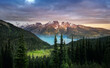 Glacial mountain Garibaldi lake with turquoise water in the middle of coniferous forest at sunset. View of a mountain lake between fir trees. Mountain peaks above the lake lit by sunset rays. Canada