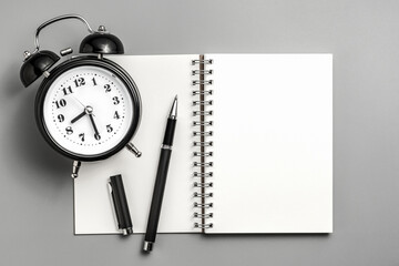 Notebook with pen and clock on gray board