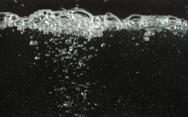 Wall Mural - Water splashing as it's poured into aquarium tank, black background