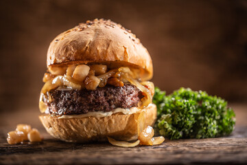 Wall Mural - Beef burger with melted cheese, caramelized onions in a sesame bun with salad on the side