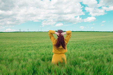  A girl with thick red voluminous hair in a wheat field is happy and enjoys fresh air and freedom. Harvest festival