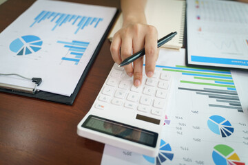 Businesswoman working from home with a calculator and financial report on wooden table.