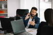 © JustLife - Businessman in office. Handsome man talking on phone at work.