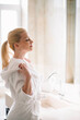 © JustLife - Beautiful woman enjoying in hotel. Young happy woman in bathrobe use the cream for the body.