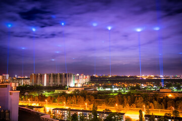 Canvas Print - Night illuminated city with blue lights in the clouds and sky