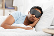 people, bedtime and rest concept - indian man in eye mask sleeping in bed at home