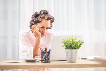 Canvas Print - Unhappy housewife frowns at computer screen wearing hair rollers and nightdress