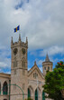 Bridgetown, Barbados, Caribbean - 22 Sept 2018: Parliament building with flag and clock tower. White clouds in the blue sky. Copy space. Vertical