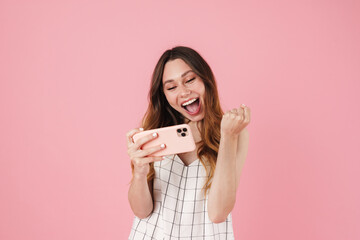 Canvas Print - Image of excited cute woman using cellphone and making winner gesture