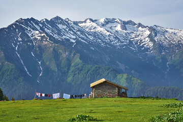 Traditional house of Sal Plateau with the background of snowy mountains and sea of clouds. Landscape photo was taken at Sal Plateau, Rize, northeastern Karadeniz (Black Sea) region of Turkey.