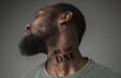 © master1305 - Close up portrait of a black man tired of racial discrimination has tattooed slogan we are one on his neck. Concept of human rights, equality, justice, problem of violence and racism, discrimination.