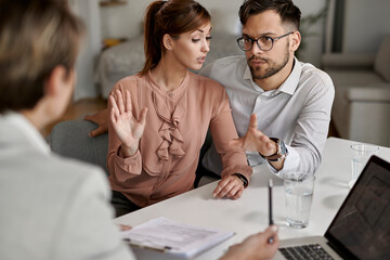 Wall Mural - Young couple communicating with insurance agent during a meeting.