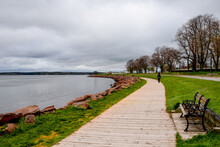 Wooden Walkway Edges With Red Rocks And Flowers Winds Around Bay In Charlottetown, Canada.