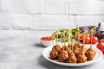 Beef meatballs stewed in tomato sauce on a plate on barbecue skewers. Light concrete background. Copy space.