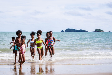 Wall Mural - African American, Kids group in swimwear enjoying running to play the waves on beach. Ethnically diverse concept. Having fun after unlocking down from COVID 19. Summer holidays on beach with friends