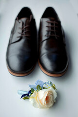 Classic black men's shoes and wedding boutonniere on a white table