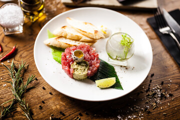 Tuna tartare: Guacamole quail egg baguette on a plate. Delicious healthy raw food closeup served for lunch on a table in modern gourmet cuisine restaurant