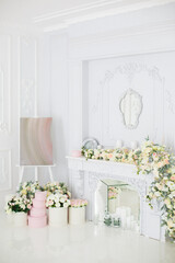 Wall Mural - Elegant white fireplace full of flowers. Elegant white room decorated with easel and hat boxes. Wedding decorated area. Vintage decor in light interior