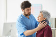 © AnnaStills - Male bearded doctor examining the neck of senior woman he putting a bandage around her neck at hospital