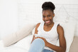 © Alexandr - beautiful young african woman sitting on bed with phone