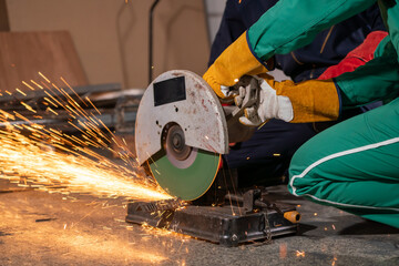 Wall Mural - Professional mechanic man is cutting steel metal with rotating carbon blade cutter. Steel industry and workshop concept.