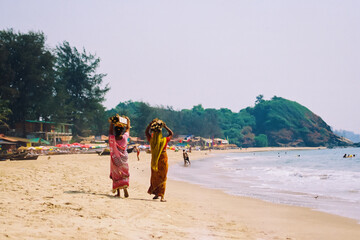 
Indian women carrying firewood on the Goa beach