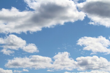 White fluffy clouds on a background of blue sky in summer. The concept of weather and climate.