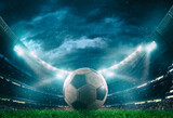 Fototapeta Sport - Close up of a soccer ball in the center of the stadium illuminated by the headlights