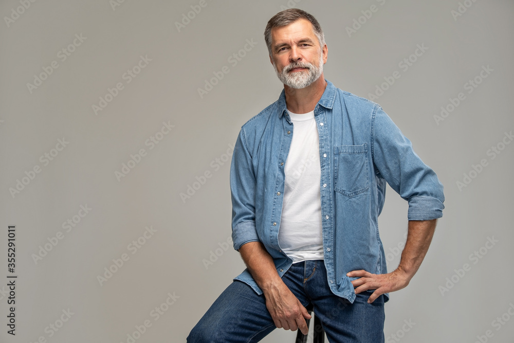 Portrait of a casual senior sitting on a chair on white background. - obrazy, fototapety, plakaty 