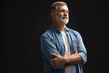 Wall Mural - Portrait of smiling mature man standing on black background.