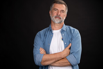 Wall Mural - Portrait of smiling mature man standing on black background.