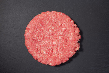 Fresh raw burger on a black stone plate. Top view.