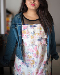 Wall Mural - Indian Bengali beautiful and cute brunette girl in a casual blue jeans shirt and white top is standing if front of a dinning table in a casual way inside a room. Indian lifestyle and fashion portrait