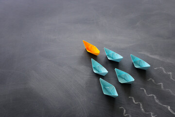 Poster - Leadership banner concept with paper boat on blackboard background. One leader ship leads others