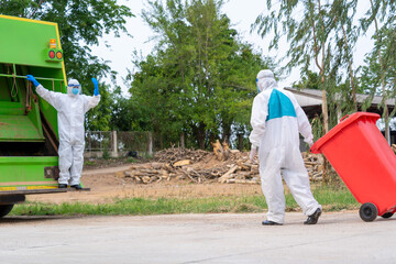 Wall Mural - Worker in hazmat PPE protective clothing wearing protective mask to Protect Against Covid-19 are loading waste with garbage collector truck.