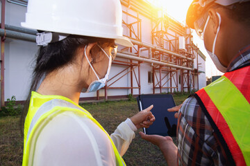 engineer discusses technical documentation with his help in the territory of a modern plant.Engineers working in the power plant area