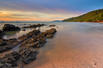 Wall Mural - Landscape view from sandy beach of Pulau Sayak with pil of rock as foreground. Soft focus effect due to long exposure technique