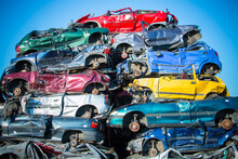 Stacked Old Cars On A Yunk Yard In Different Colours With A Blue Skye