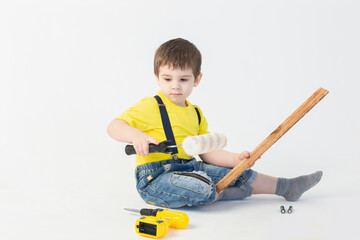 Wall Mural - a small boy in a Builder's suit makes repairs on a white background