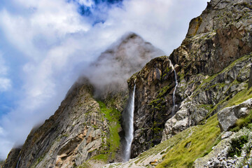 Wall Mural - Stunning landscape at roaring Vasudhara falls, people enjoying the fall, big rocky mountains and clouds. Monsoon trek taken in August starts near Mana (last indian village) in Uttarakhand India.